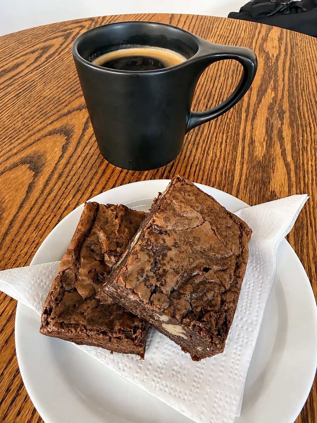 Chocolate brownies with a black coffee on a wooden table