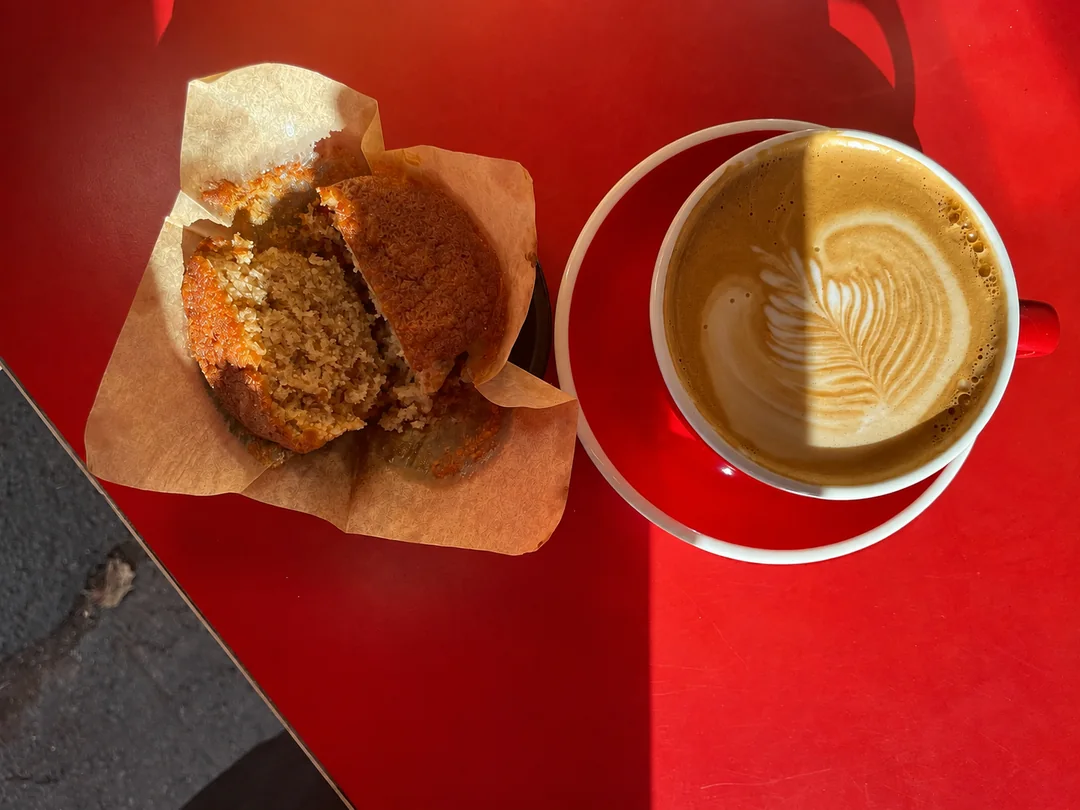 A muffin and coffee on a red café table