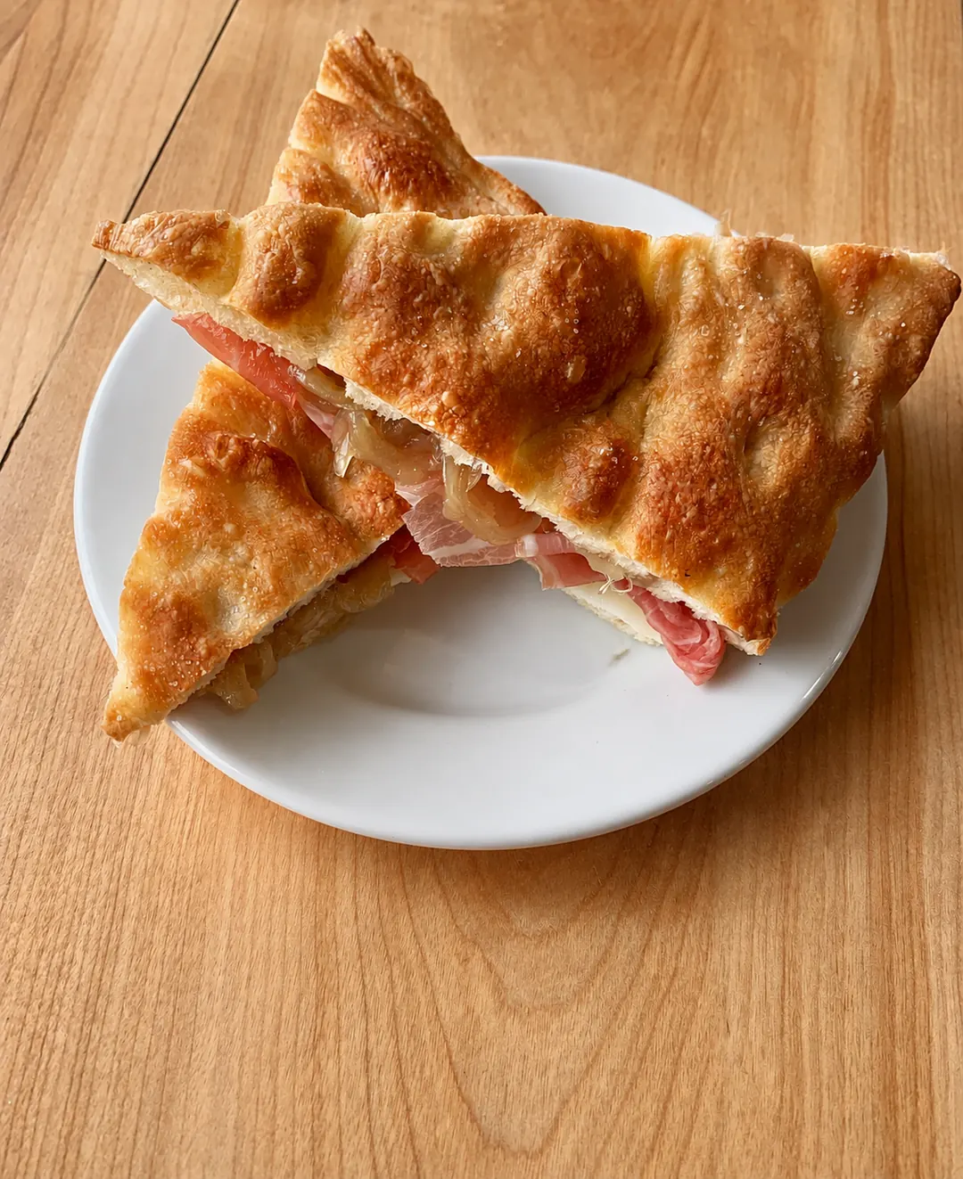 Two pieces of a filled focaccia sandwich on a white plate