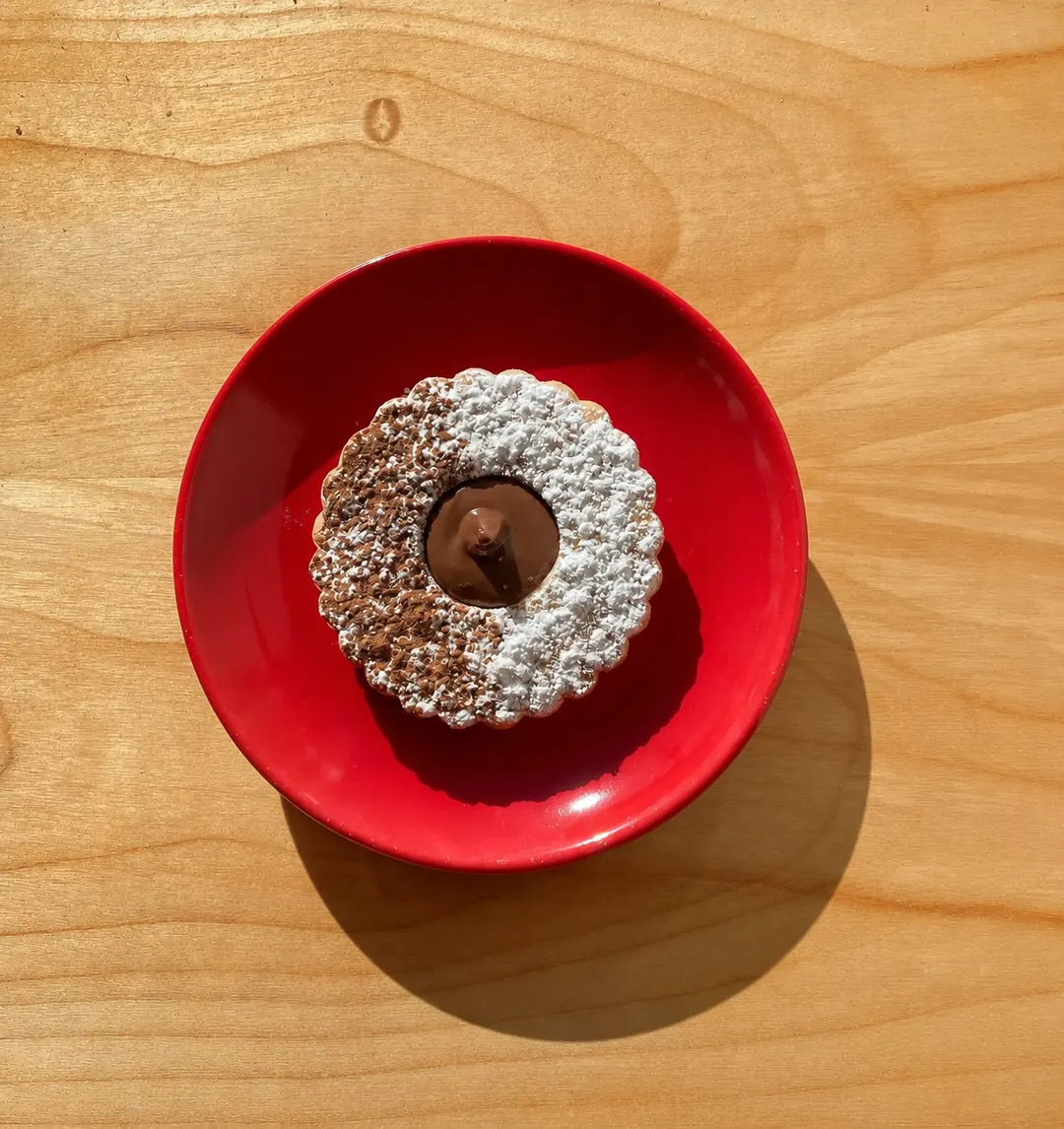 A chocolate-filled biscuit on a red saucer